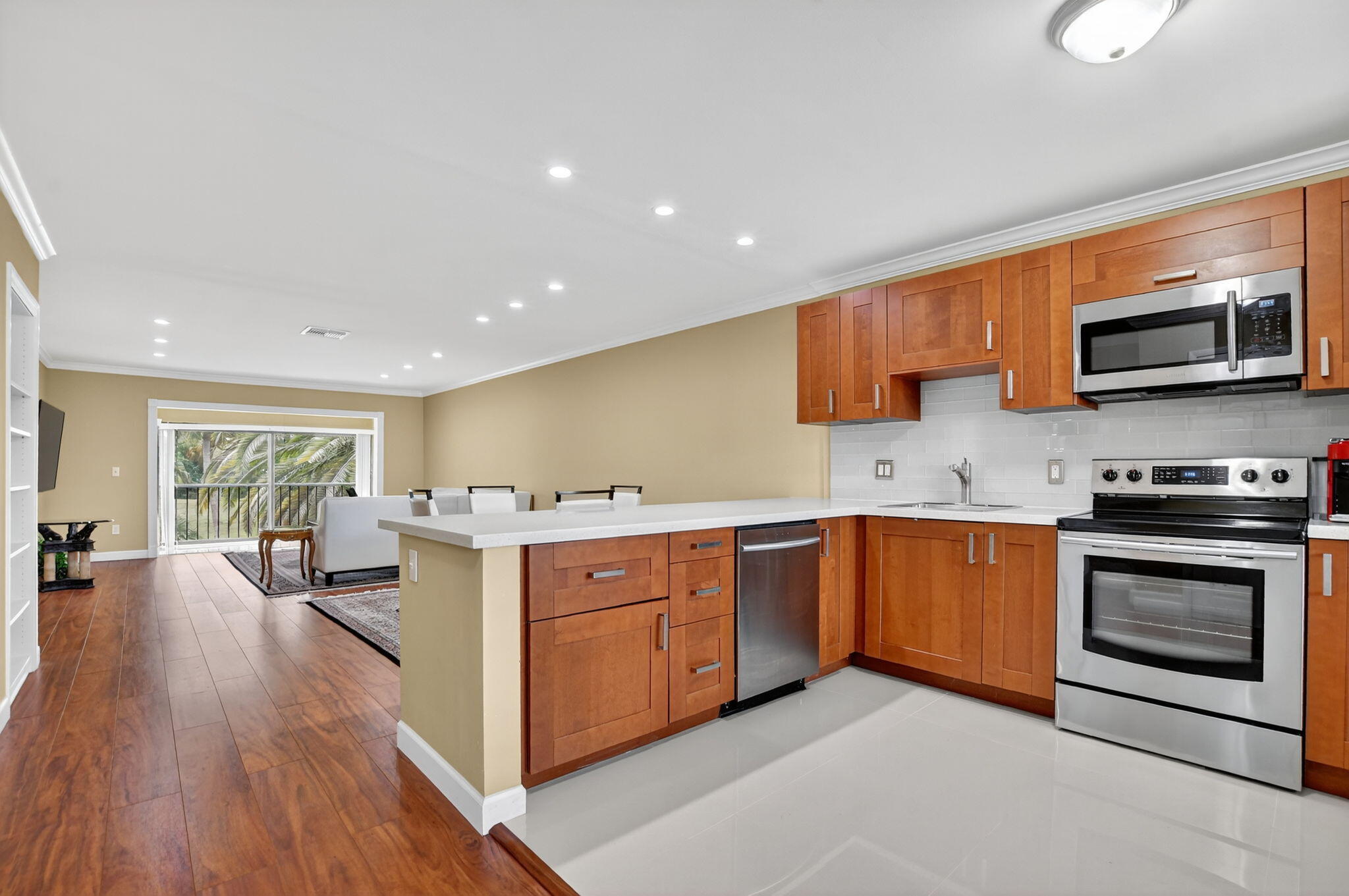 9268 Vista Del Lago, Unit 26D Boca Raton, FL 33428 - Photo 6 of 34 a large kitchen with stainless steel appliances granite countertop a stove a sink dishwasher and a microwave oven with wooden floor