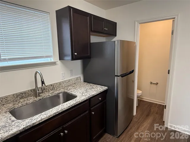 a kitchen with granite countertop a refrigerator and a sink