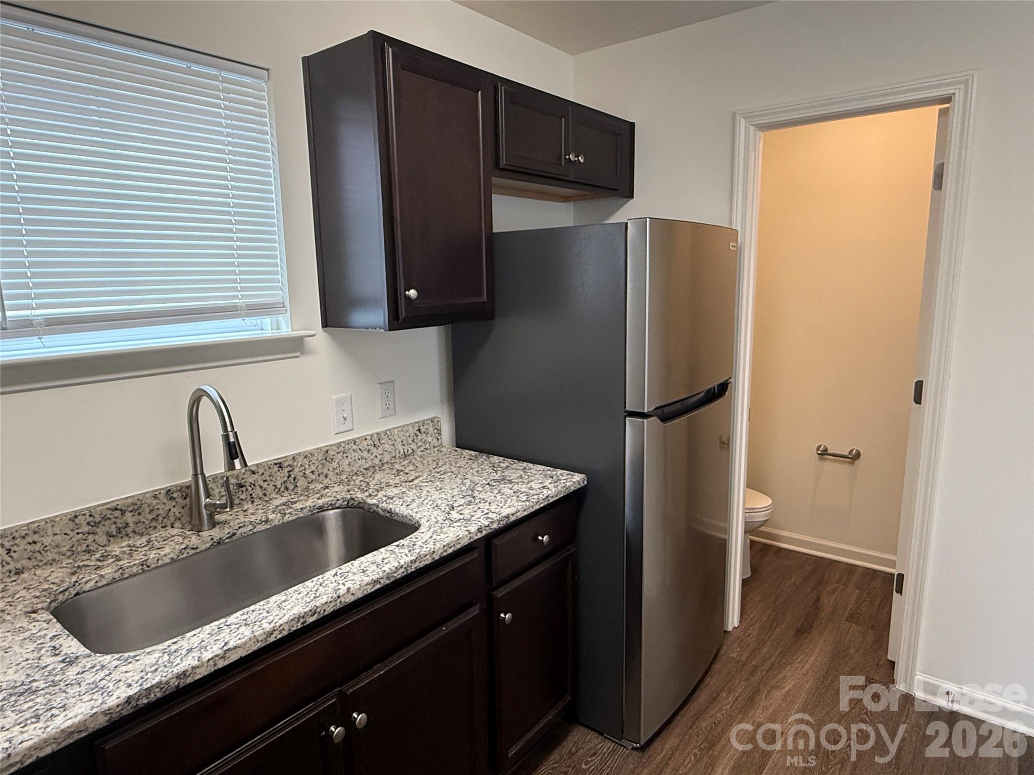 2021 Oakdale Road, Unit K Charlotte, NC 28216 - Photo 5 of 13 a kitchen with granite countertop a refrigerator and a sink