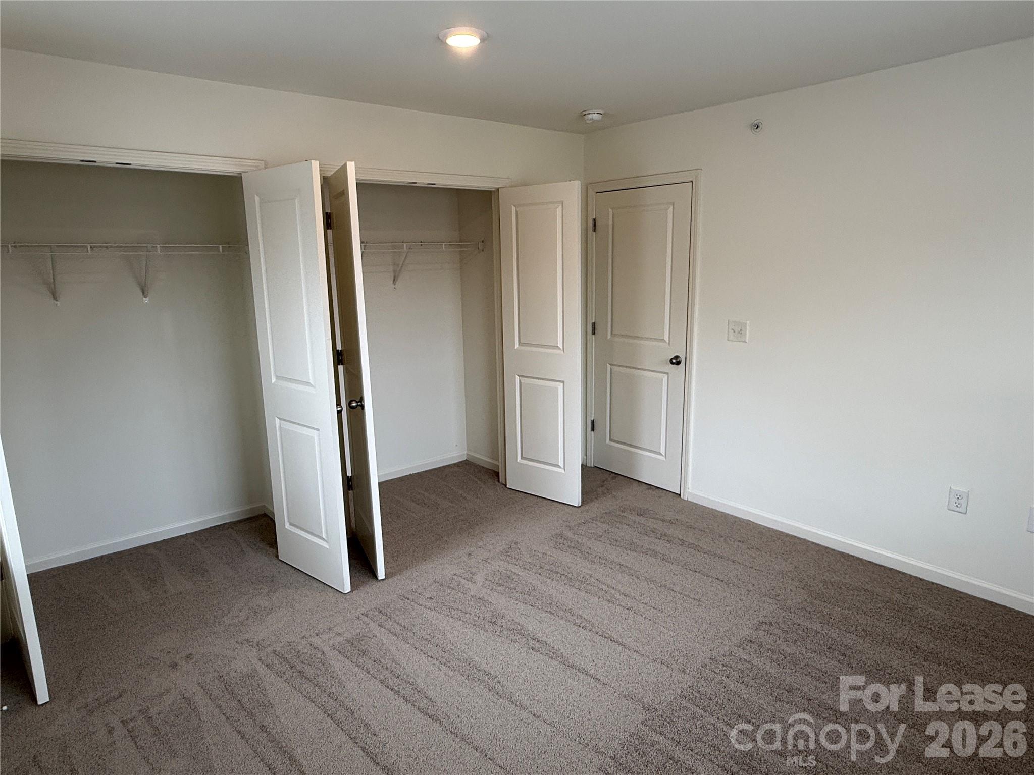 2021 Oakdale Road, Unit K Charlotte, NC 28216 - Photo 7 of 13 an empty room with wooden floor and closet area