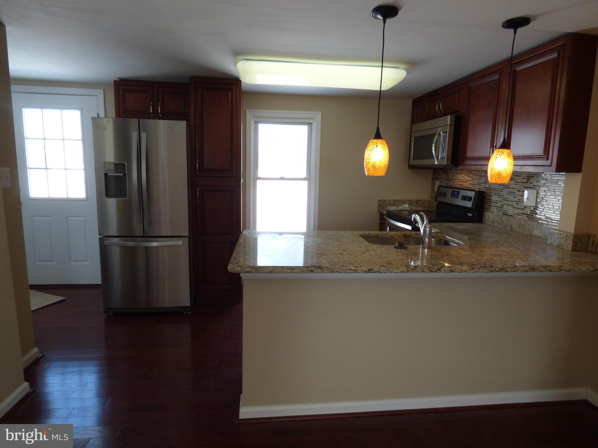 2064 Bethel Road Finksburg, MD 21048 - Photo 9 of 30 a kitchen with granite countertop a refrigerator a stove and wooden floor