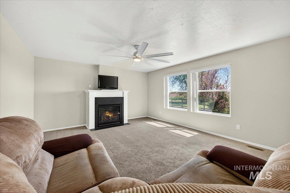 1555 Condor Drive Middleton, ID 83644 - Photo 15 of 50 Living area featuring a floor-to-ceiling fireplace with a white mantel, light-toned carpeting, dual windows, and a ceiling fan with integrated lighting