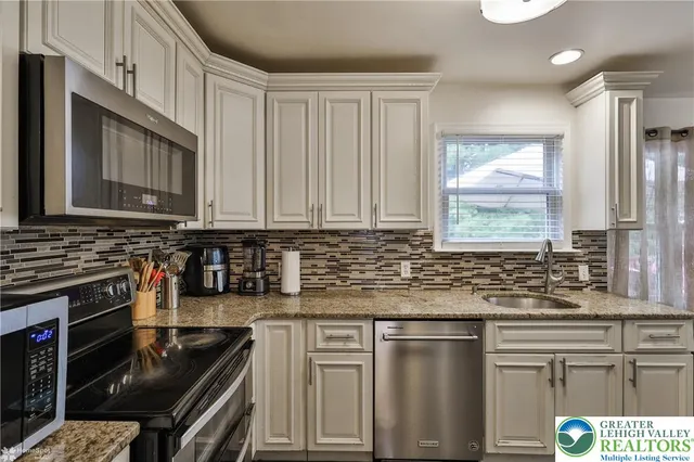 a kitchen with stainless steel appliances granite countertop a stove a sink and a microwave