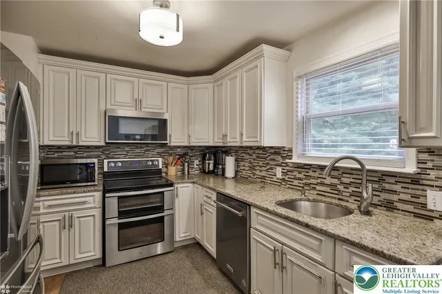 a kitchen with granite countertop a sink stainless steel appliances and white cabinets