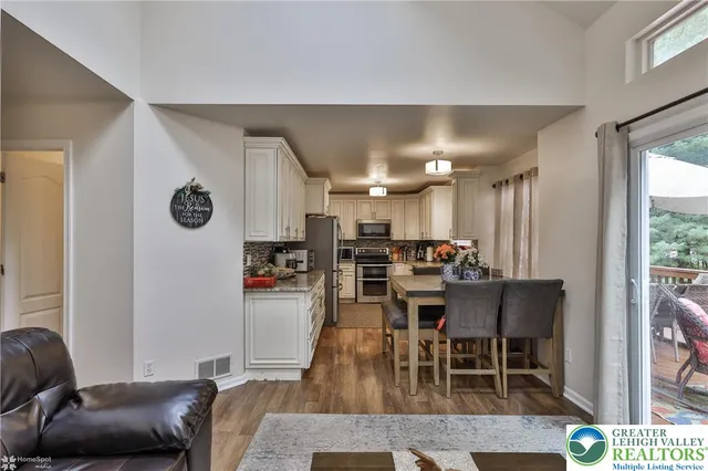a living room with stainless steel appliances furniture a rug and a kitchen view