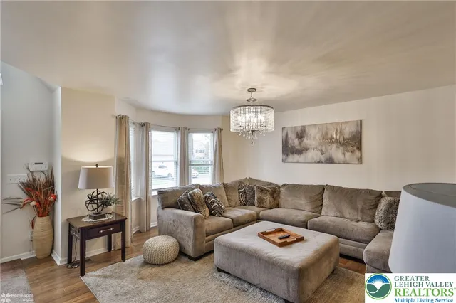 a living room with furniture a chandelier and a large mirror next to a window