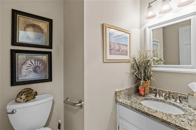 a bathroom with a granite countertop toilet a sink and mirror