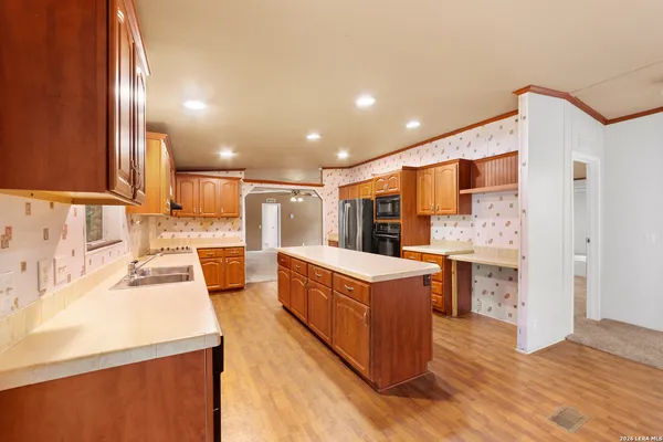 a large kitchen with stainless steel appliances a large counter top a stove and a refrigerator
