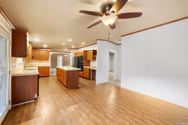 a living room with couches and kitchen view with wooden floor
