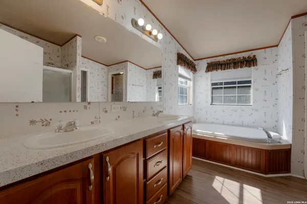 a bathroom with a sink double vanity granite tub and a mirror