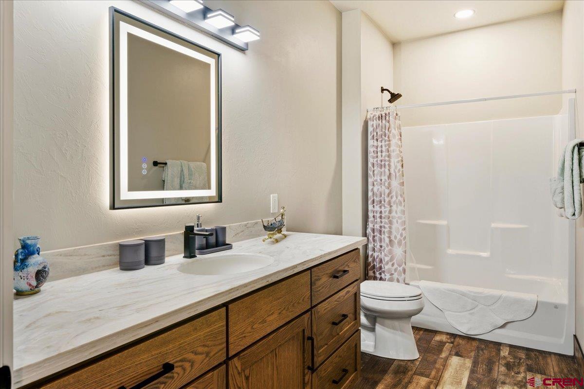 11266 5880 Road Montrose, CO 81403 - Photo 25 of 43 a bathroom with a granite countertop sink toilet a mirror and shower