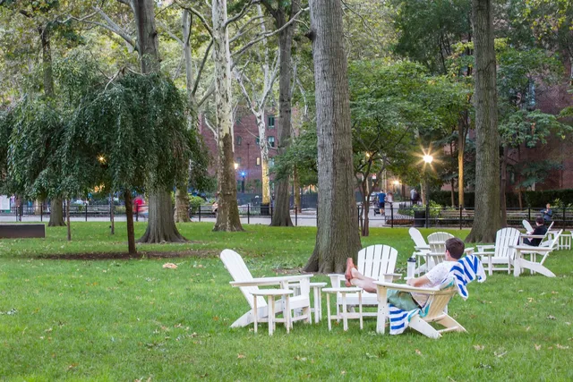a table and chairs sitting in the grass near a park