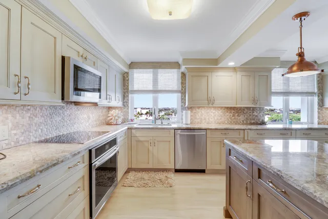 a large kitchen with granite countertop a stove a sink a window and dining table