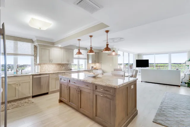 a kitchen with stainless steel appliances kitchen island granite countertop a table chairs sink and cabinets