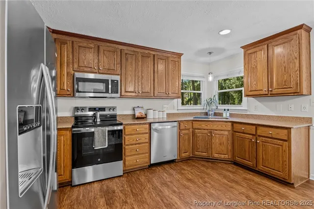 a kitchen with stainless steel appliances granite countertop wooden cabinets a stove top oven a sink and dishwasher