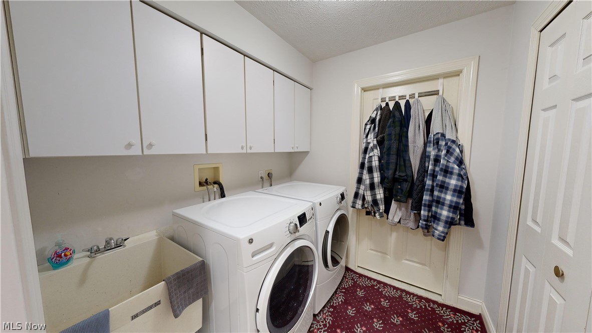 7115 Brakeman Road Painesville, OH 44077 - Photo 20 of 47 Clothes washing area featuring cabinets, washing machine and clothes dryer, sink, and a textured ceiling