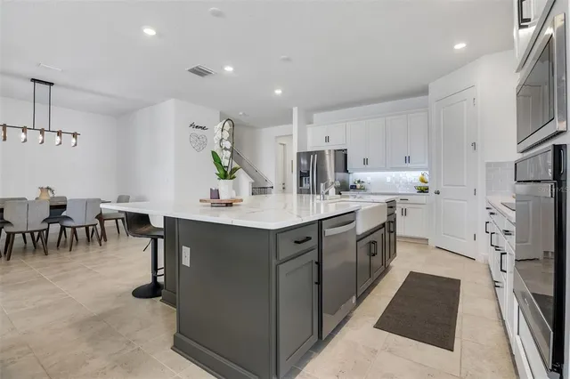 a kitchen with stainless steel appliances kitchen island granite countertop a table chairs sink and cabinets