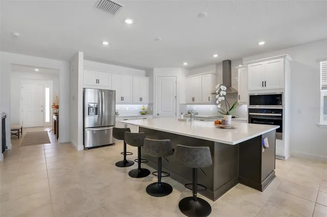 a kitchen with stainless steel appliances kitchen island granite countertop a sink refrigerator and cabinets