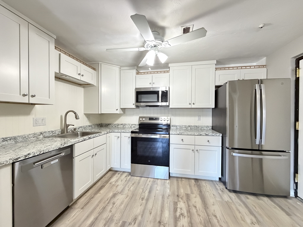 a kitchen with granite countertop a refrigerator stove a sink and dishwasher with wooden floor