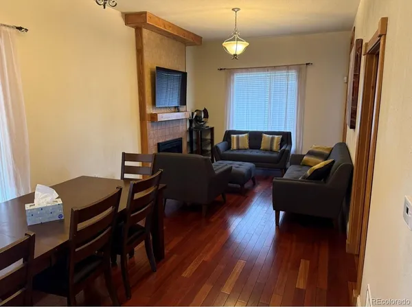 a living room with stainless steel appliances furniture a rug and a view of kitchen