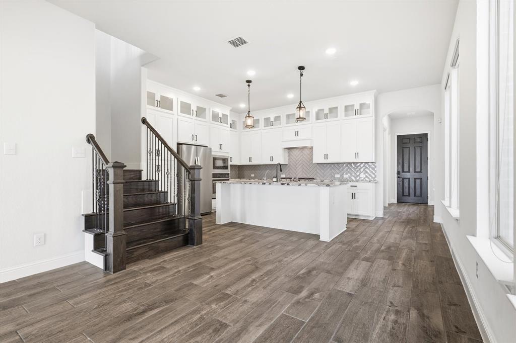 18140 Lakefront Court Forney, TX 75126 - Photo 11 of 37 Kitchen featuring white cabinets, appliances with stainless steel finishes, a kitchen island with sink, hanging light fixtures, and dark wood-style flooring