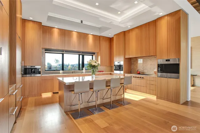 a living room with a large window and a kitchen view
