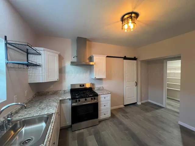 a kitchen with granite countertop a refrigerator and a stove top oven