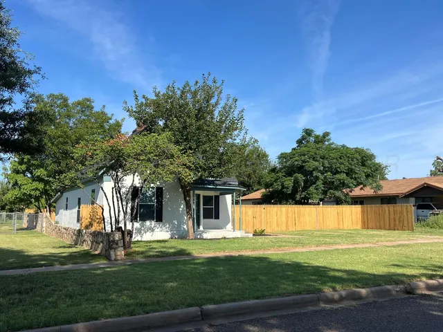 a front view of a house with a garden and trees