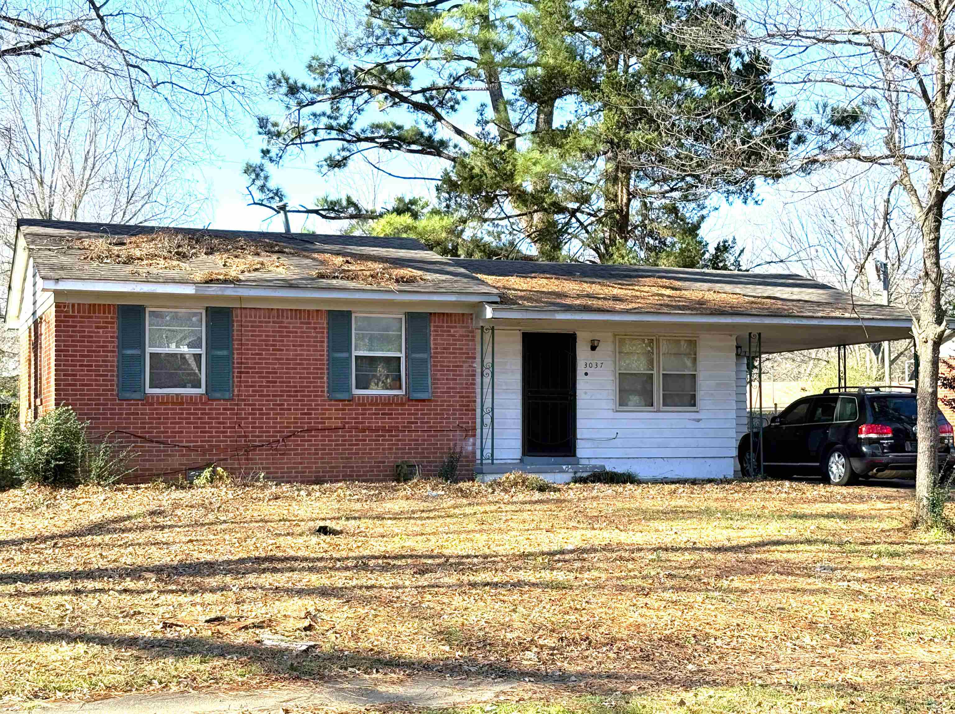 Single story home with a carport, brick siding, a porch, and a front lawn