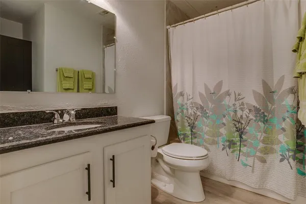 a bathroom with a granite countertop sink a toilet and a mirror