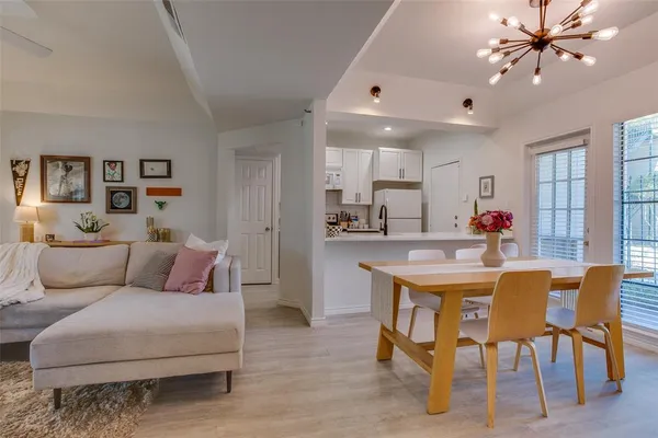 a living room with furniture kitchen view and a chandelier