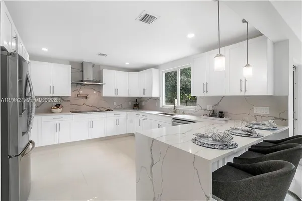a kitchen with a sink a stove a refrigerator and white cabinets