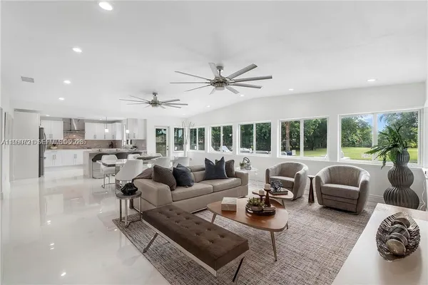 a living room with furniture ceiling fan and a large window