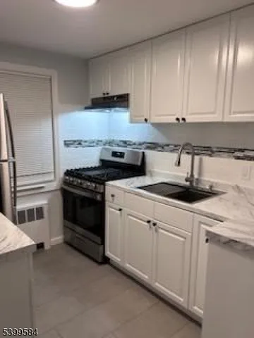 a kitchen with granite countertop white cabinets and stainless steel appliances