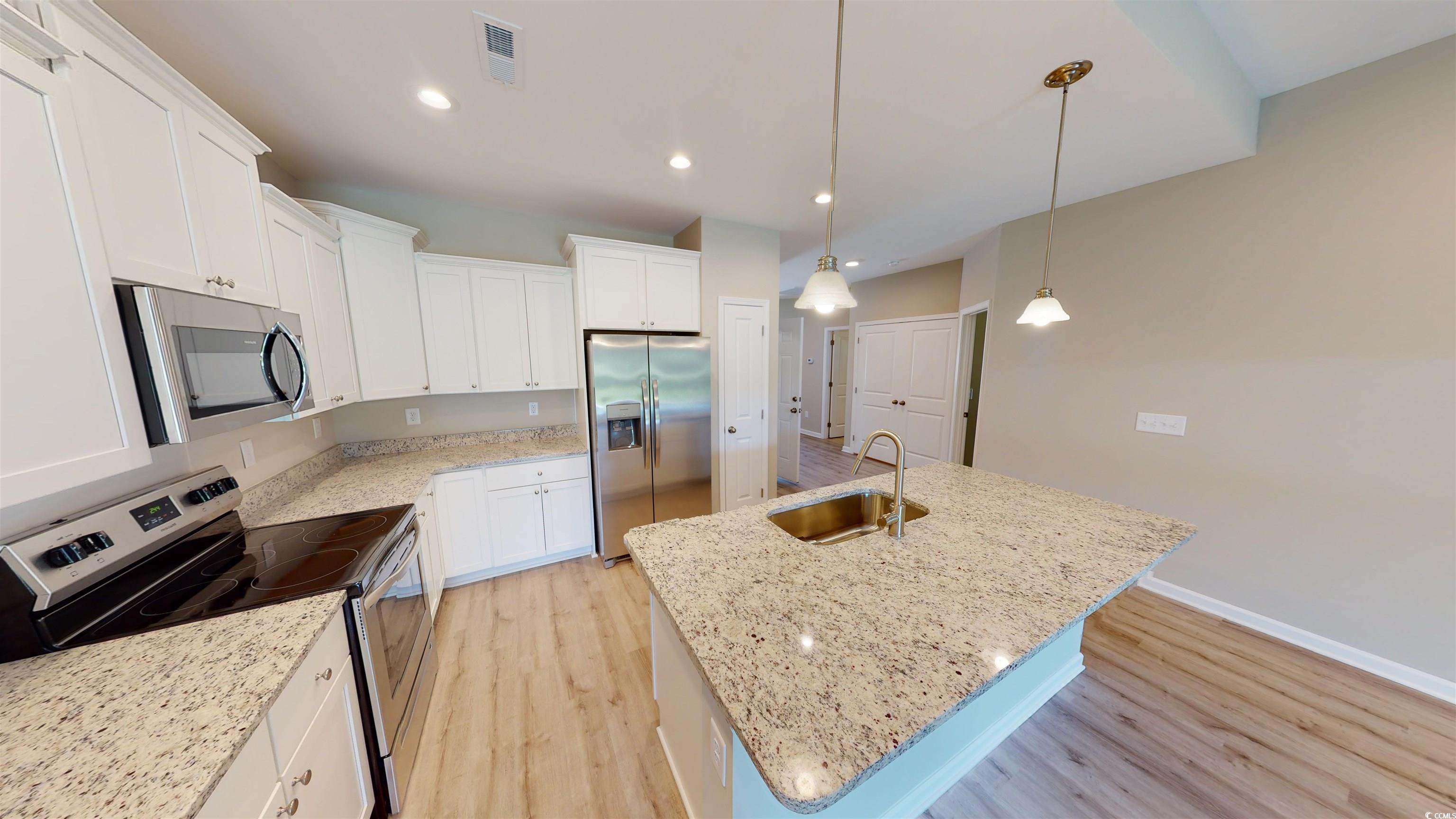 84 Racquet Club Drive, Unit WVC 14 Pawleys Island, SC 29585 - Photo 10 of 26 Kitchen with light wood-type flooring, appliances with stainless steel finishes, a kitchen island with sink, recessed lighting, and light stone countertops