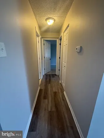 a view of a hallway with wooden floor and a bathroom