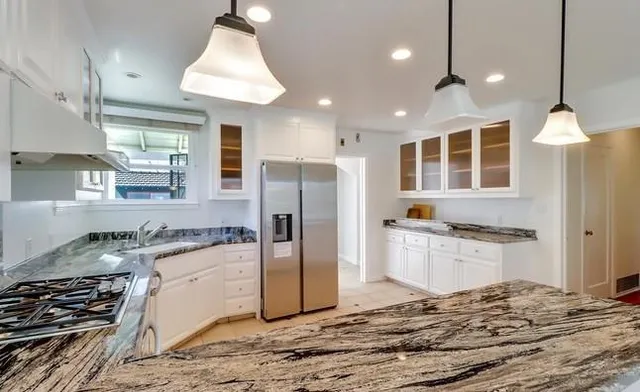 a kitchen with stainless steel appliances granite countertop a sink a stove a refrigerator and cabinets
