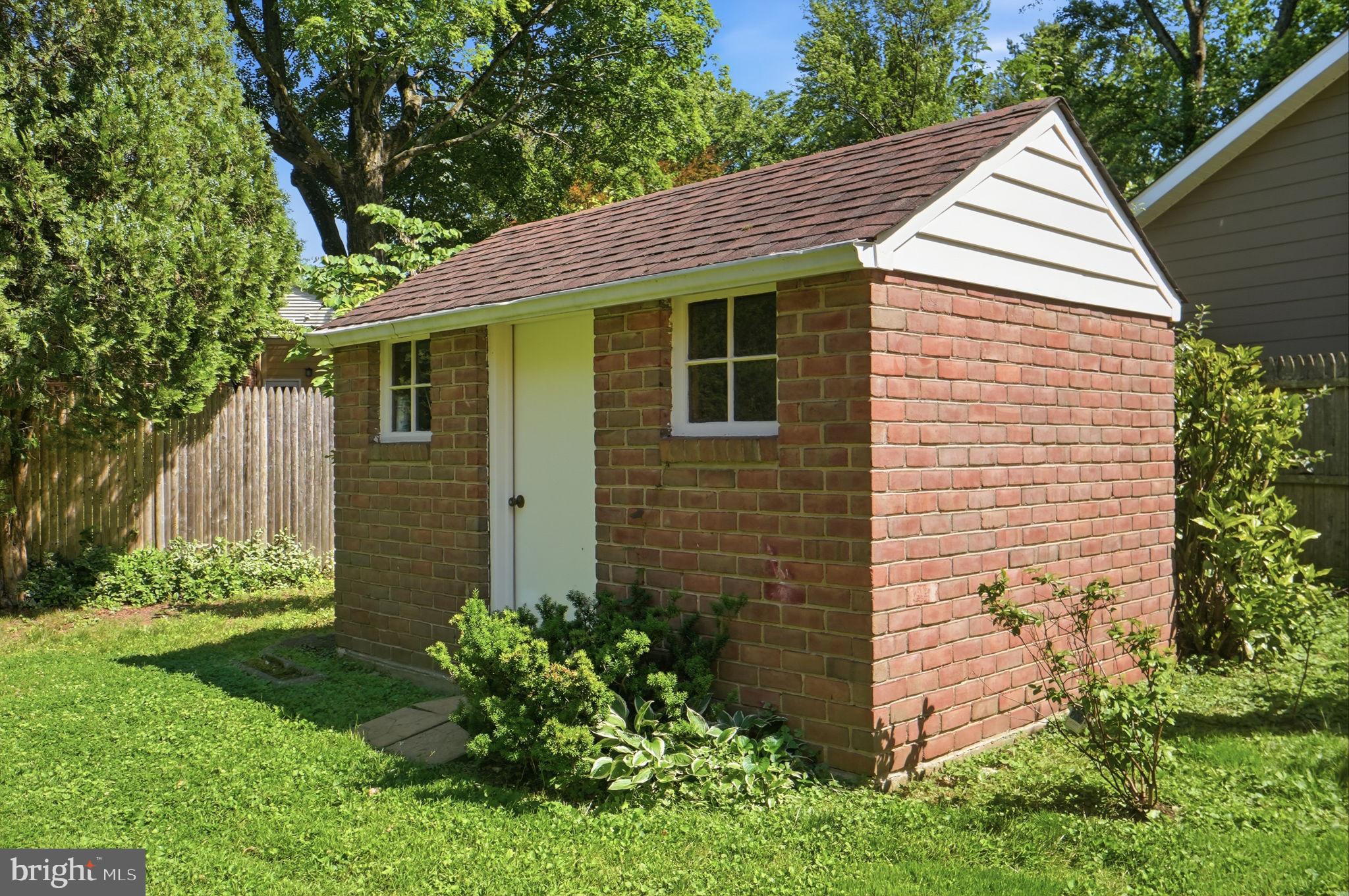 8008 Inspection House Road Potomac, MD 20854 - Photo 42 of 43 Charming brick shed in lush greenery.