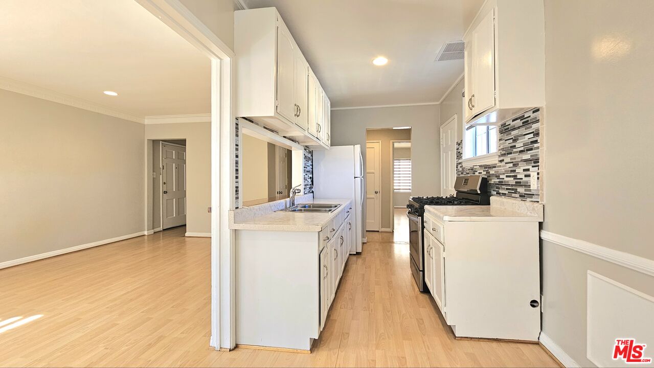 1022 South Norton Avenue, Unit C Los Angeles, CA 90019 - Photo 16 of 43 a kitchen with kitchen island sink stove and white cabinets