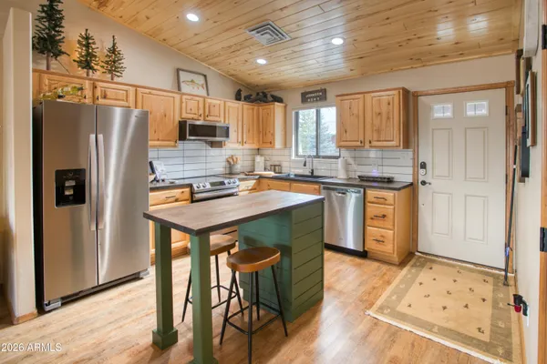 a kitchen with stainless steel appliances granite countertop a refrigerator a sink dishwasher a stove and white countertops with wooden floor