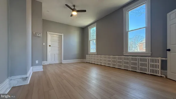 an empty room with wooden floor and windows