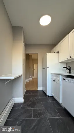 a kitchen with a refrigerator and white cabinets