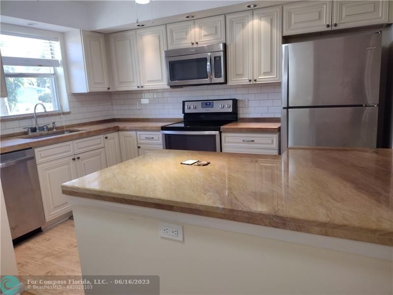 a kitchen with stainless steel appliances granite countertop a sink a stove a refrigerator a microwave and cabinets