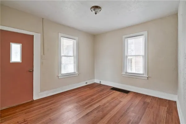 a view of an empty room with wooden floor and a window