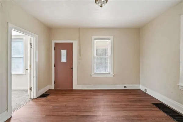 an empty room with wooden floor and windows