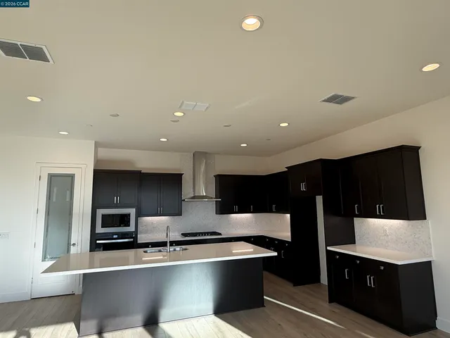 a large kitchen with stainless steel appliances a sink and cabinets