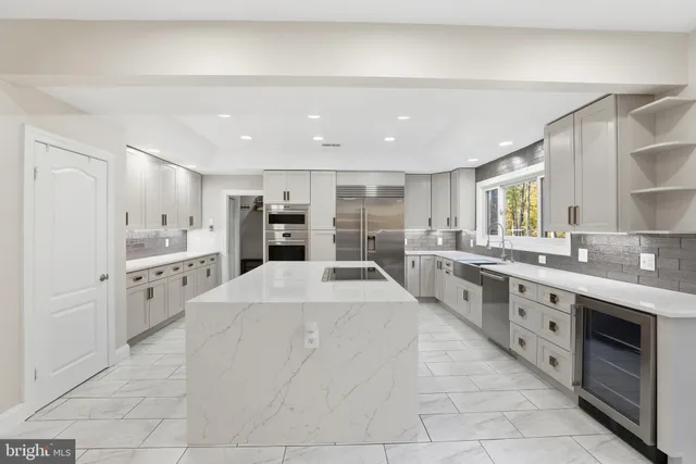 a large white kitchen with stainless steel appliances a stove a sink and a refrigerator