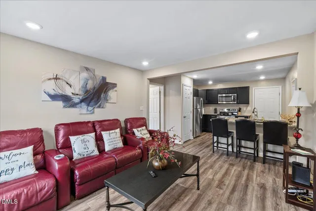 a living room with furniture kitchen view and a wooden floor