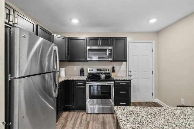 a kitchen with stainless steel appliances granite countertop a refrigerator a stove a sink and a microwave