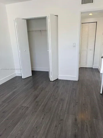 an empty room with wooden floor and closet